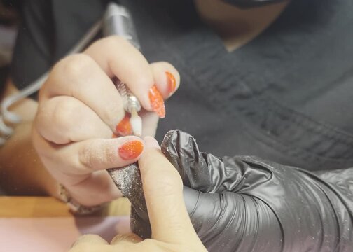 Nail technician removing rubber using a nail drill to make a new nail design