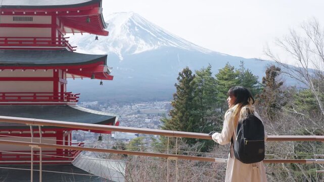 Asian woman tourist visiting Chureito Pagoda with Mount Fuji in Japan. Female traveler sightseeing traditional Japanese landmark, winter vacation, cultural tourism and scenic mountain travel