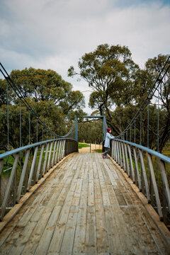 Side view of a woman standing on a timber suspension bridge and enjoying the nature, Donald, Victoria, Australia