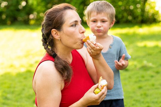 Mother Eating Ice Cream Beside Young Son Outdoors