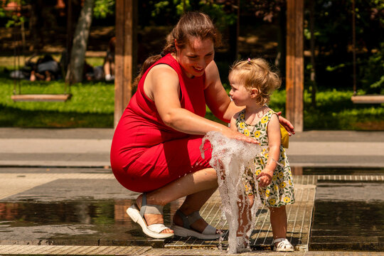 Mother and Toddler Daughter Playing With Fountain Water