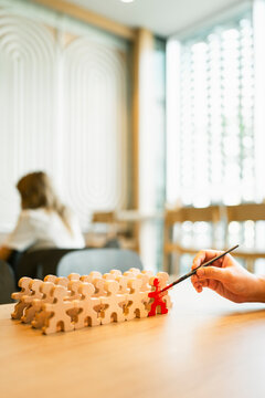 Leadership and talent recruitment concept with hand painting wooden figure in red among group on table for career promotion, employee training, standout individuality and business growth.