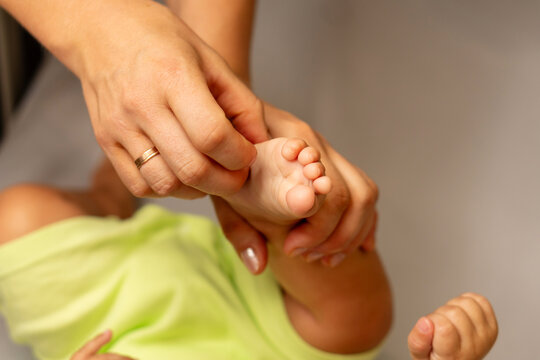 Mother Playfully Tickling Bare Foot Of Infant Son