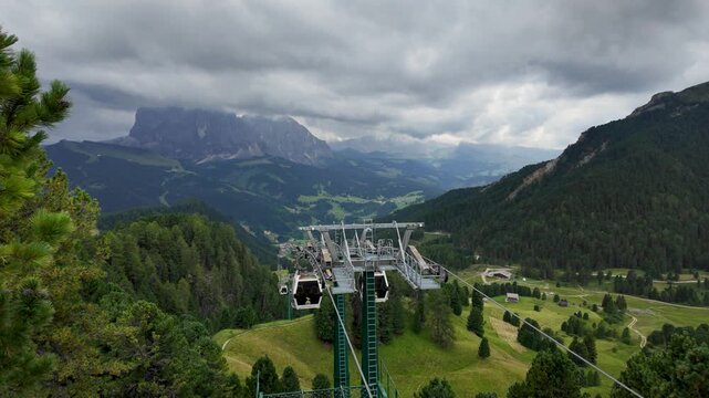 Slow motion pullback through a wooden viewing frame at Seceda meadow, revealing rugged limestone mountains, alpine grassland, scattered trees, and dramatic low clouds in the Val Gardena landscape