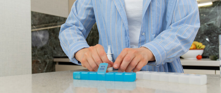 Woman methodically fills pill organizer with vitamins and supplements