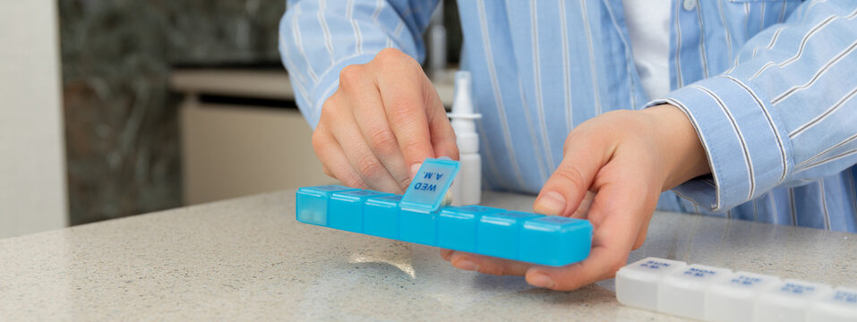 Person organizes vitamins and medications in a pill organizer