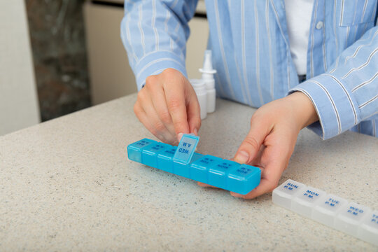 Person organizes daily vitamins in pill organizer for effective health management