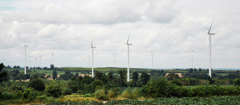 Wind turbines generating clean energy across a lush green landscape under cloudy skies.