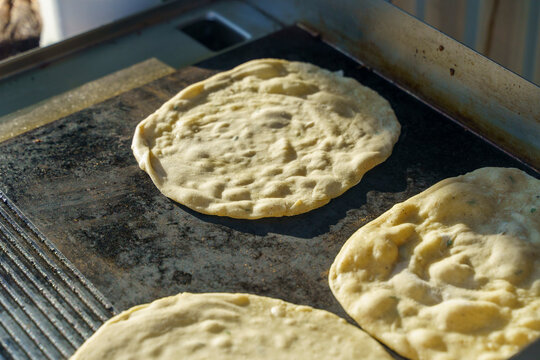 Flatbreads cooking on a hot iron griddle grill outdoor