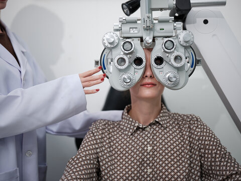 Close-up, female patient eye exam with phoropter equipment, vision and eyesight improvement by expert optometrist, diagnostic for eyeglasses lens, professional technology services in optical clinic.