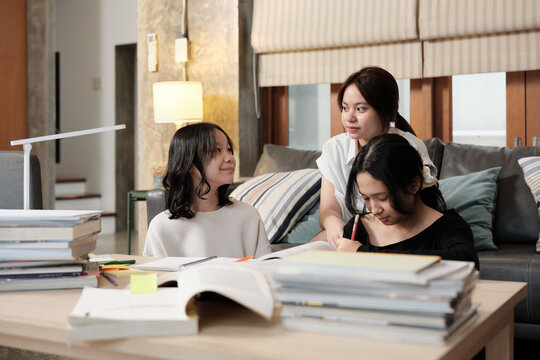 Three Asian teenage girls learning tutorials at home together, reading textbooks, writing notes, self-tutorial exams, preparing school homework, Homeschooling study, knowledge education lifestyle.