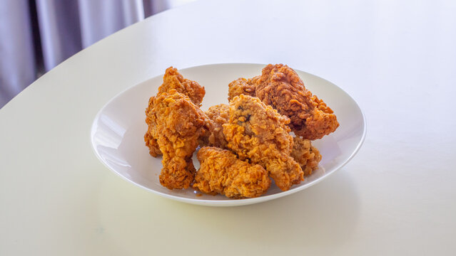 Crispy spicy fried chicken in white plate on wood table