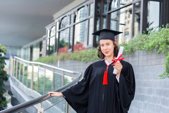 Happy young woman with diploma on graduation day