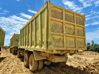 Industrial dump truck operating on rough muddy terrain during earthmoving work © Raditya
