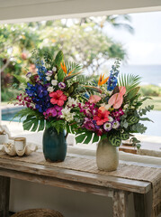 Fototapeta premium Two tropical flower arrangements in ceramic vases on wooden table for elegant summer home interior decor displays.