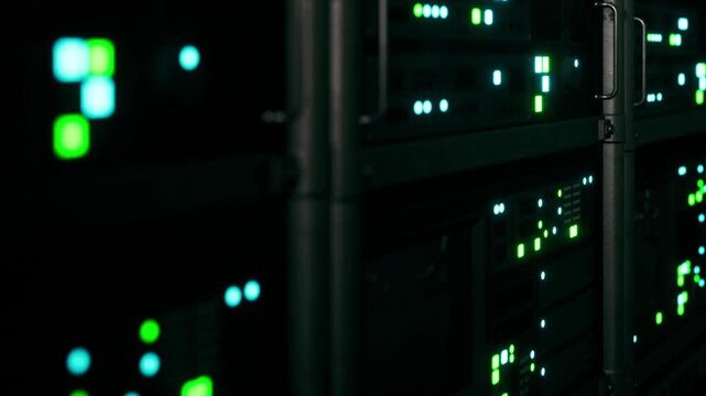 A data center filled with servers. Bright lights in green and blue are seen on the front of the machines. The image captures the technology working at night.