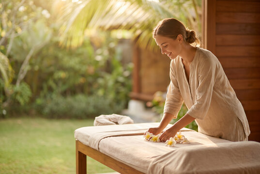 Woman arranging flowers on outdoor massage table in tropical garden
