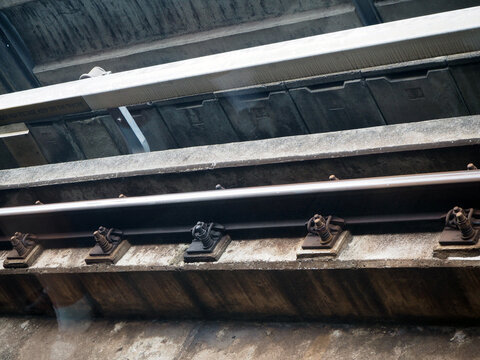 Close-up view of train tracks on a bridge, showing the concrete structure and metal rails