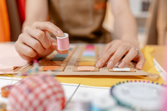 Professional fashion designer measuring fabric, selecting colors and preparing sewing equipment in a modern studio. Creative garment production, textile craftsmanship and apparel design.