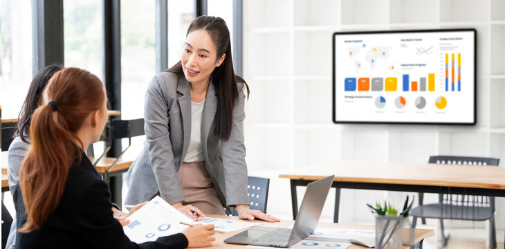 Asian Business Woman Standing and Leading Financial Presentation in Office Meeting