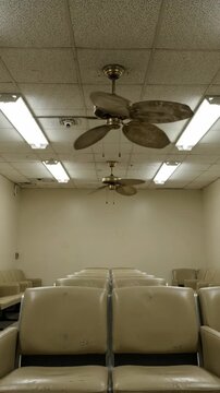 Empty waiting room beige chair ceiling fan fluorescent light quiet slightly worn atmosphere calm and peaceful environment for relaxation