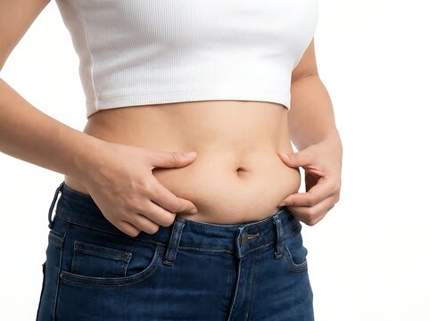 A person wearing a white crop and blue jeans pinching the excess fat on their stomach to show weight gain and body composition concerns