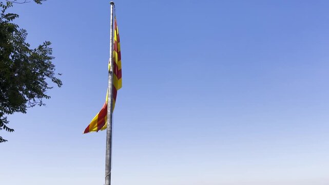 The Catalan flag waving in the wind from a flagpost.