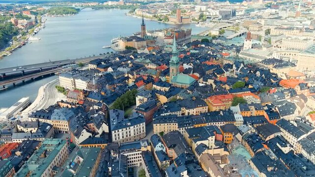 Stockholm, Sweden. Gamla Stan, aerial panorama over the medieval island district with copper spires, terracotta rooftops and the Royal Palace, summer daylight. Drone footage
