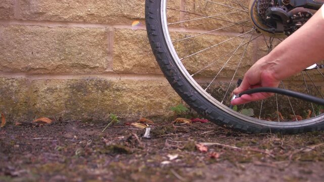 Cyclist pumping flat tyre on bicycle close up zoom slow motion shot selective focus
