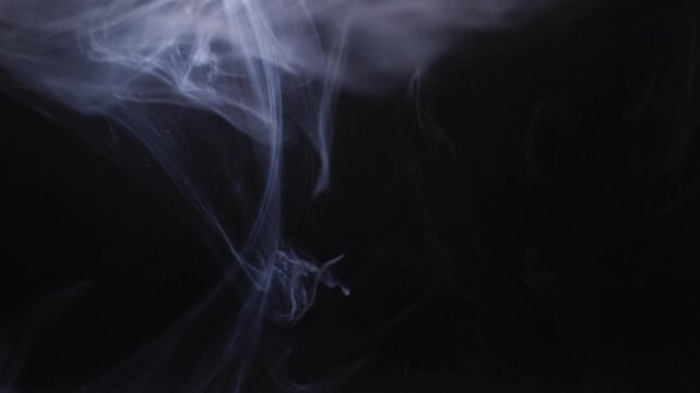 Grey swirls of smoke on black background close up zoom shot selective focus