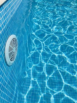 Blue tiled swimming pool water with circular drain