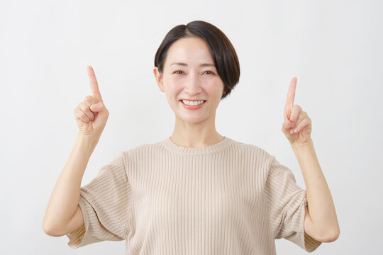 両手で上を指し示す女性　ミドルエイジ　白背.
