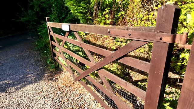 Large open brown wooden farm gate and post .