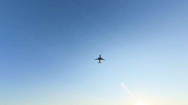 An airplane can be seen flying through the sky at sunset. The frames show different angles of the aircraft in a clear blue sky. The sun is low on the horizon.