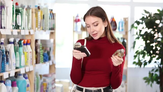 Young woman buyer testing perfume in household chemicals store 