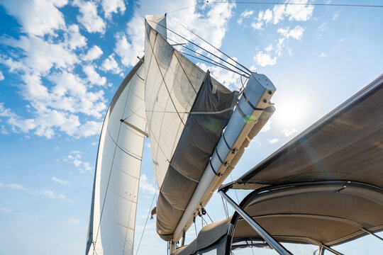 White sails filled with wind against a blue sky above a sailing yacht. Wind powered navigation and freedom at sea.