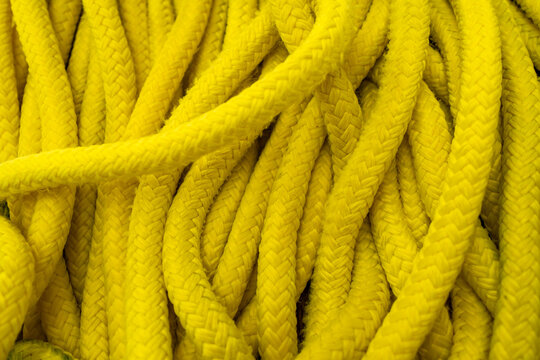 Coiled bright yellow marine rope texture in close up. Nautical safety equipment and durable braided cord background.