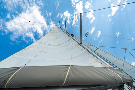 White sails filled with wind against a blue sky above a sailing yacht. Wind powered navigation and freedom at sea.