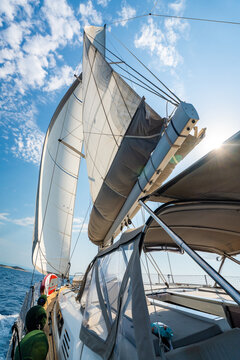 View from deck of sailing yacht with fully deployed sails cruising across Adriatic Sea under bright blue sky. Dynamic maritime travel scene representing freedom, adventure and nautical lifestyle
