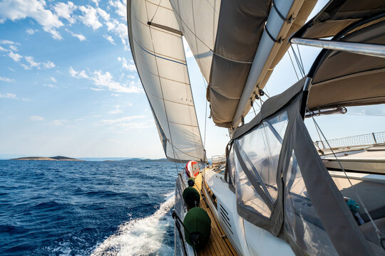 Dynamic view from deck of sailing yacht heeling under wind power while cutting through Adriatic waters. White wake, filled sails, a sense of speed, freedom and offshore adventure