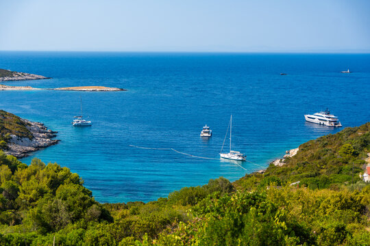 Scenic coastal bay with anchored yachts, turquoise Adriatic Sea, rocky shoreline and lush Mediterranean vegetation on Vis Island in Croatia. Ideal destination for sailing, boating and summer vacation
