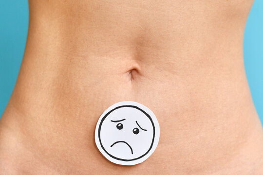 Sad face on woman abdomen symbolizing menstrual pain, endometriosis, fertility issues and reproductive health problems