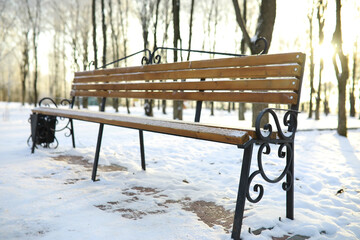 Fototapeta premium park bench on a winter alley at snowfall. bench with snow after snowstorm or in snow calamity in europe