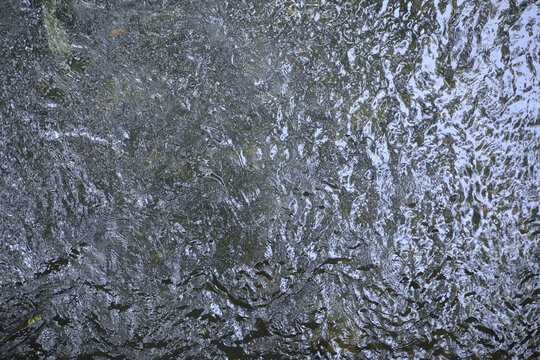 River stream blue color water flowing on stones. nature background.
