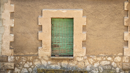 Fototapeta premium Ventana verde cerrada en pared rústica de piedra y yeso