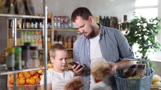 Man and son in store scan QR code on poultry parts package box. With help of mobile app, buyer receive information about product. They check manufacturers data in registry database of national agency