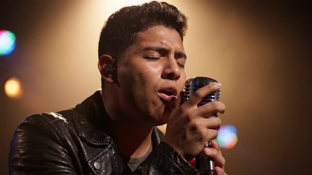 Emotional male singer passionately performing on a spotlighted stage, singing into a classic microphone during a live concert, creating a powerful musical experience