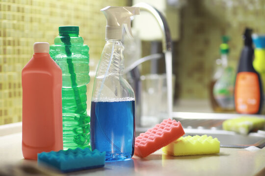 A bottle with an environmentally friendly dishwashing detergent on the background of a housewife washing dishes