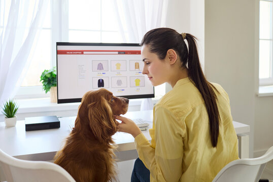 Woman and dog browsing online shopping at home. Pet cocker spaniel sits by the computer as the owner compares products, enjoying comfort and tidy workspace. Warm home bonding and online shopping.
