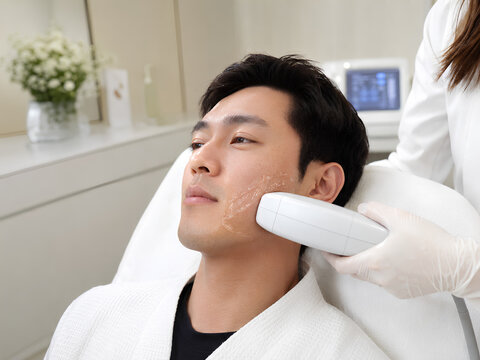 Asian man receiving HIFU facial skin tightening treatment on jawline at aesthetic clinic